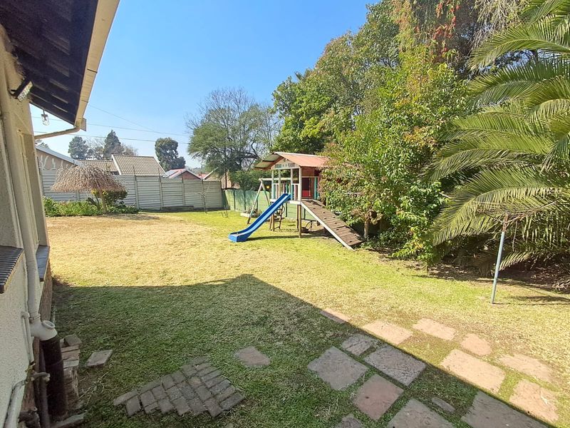 A spacious rear garden featuring a lawn, paved walkway, and precast concrete boundary wall, providing a private outdoor area.