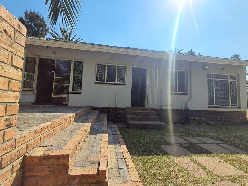 Rear exterior view of the house featuring a brick patio, steps, and security-fitted windows and doors leading into the living spaces.