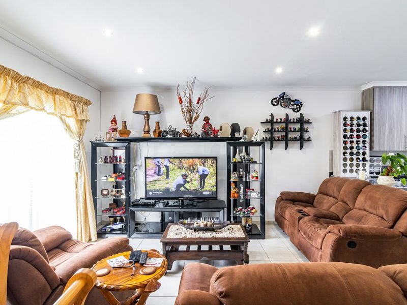 Open plan living area featuring tiled flooring, recessed downlights, and an integrated kitchen space with built-in cabinetry and a wine rack.