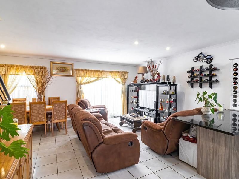 Spacious open-plan living and dining area featuring tiled flooring, recessed lighting, and a modern granite-topped kitchen counter.