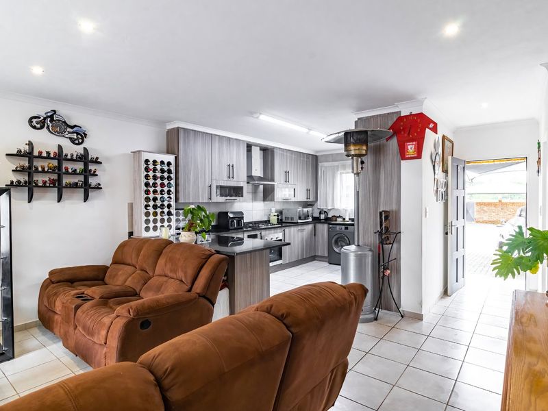 Open-plan living area featuring a modern kitchen with granite countertops, built-in cabinetry, and tiled flooring, seamlessly flowing into the main living space.
