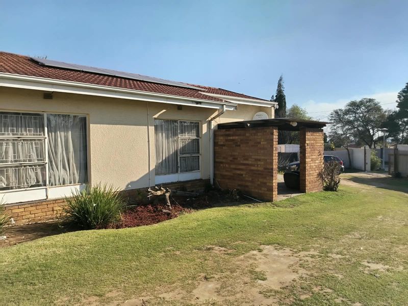 Rear view of the house featuring a tiled roof with solar panels, a brick-built patio area, and security bars on the windows.