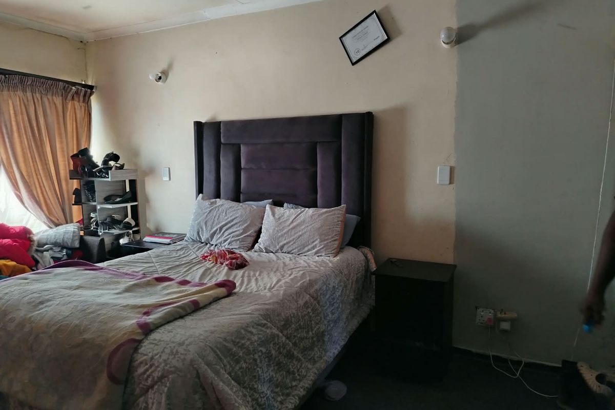 A bedroom featuring wall-mounted lighting and curtain rails, requiring cosmetic updates to the walls and ceiling to improve the overall finish.