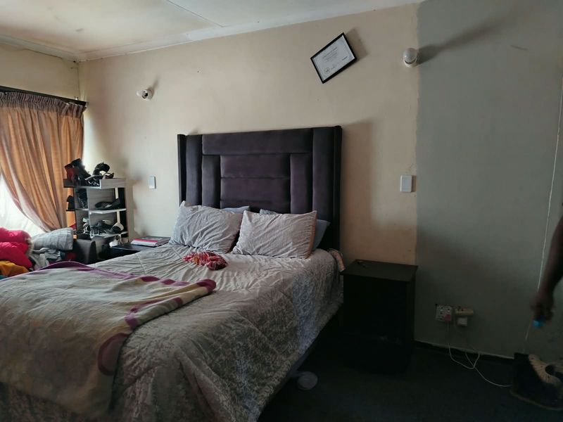 A bedroom featuring wall-mounted lighting and curtain rails, requiring cosmetic updates to the walls and ceiling to improve the overall finish.
