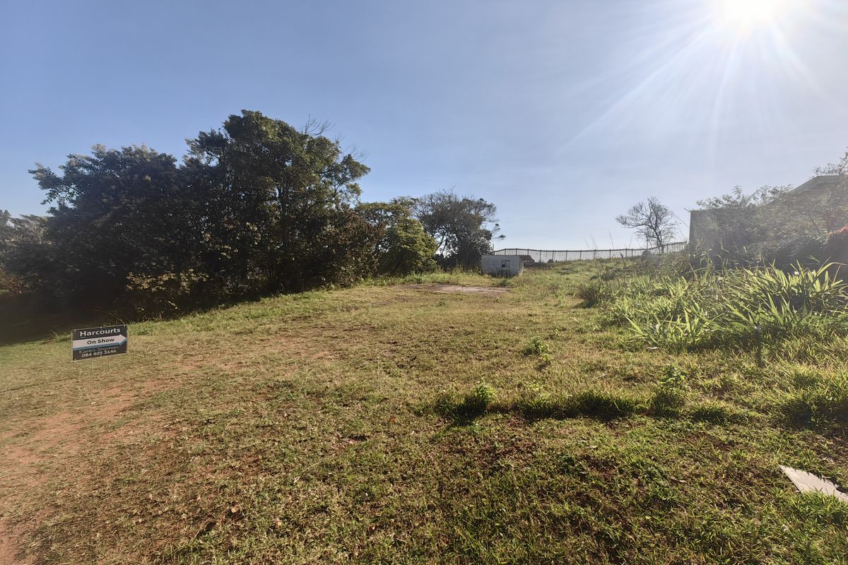A vacant residential plot featuring established trees, grass cover, and perimeter fencing, offering a clear space for future development.