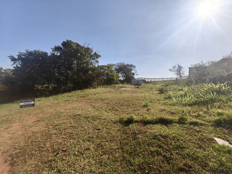 A vacant residential plot featuring established trees, grass cover, and perimeter fencing, offering a clear space for future development.
