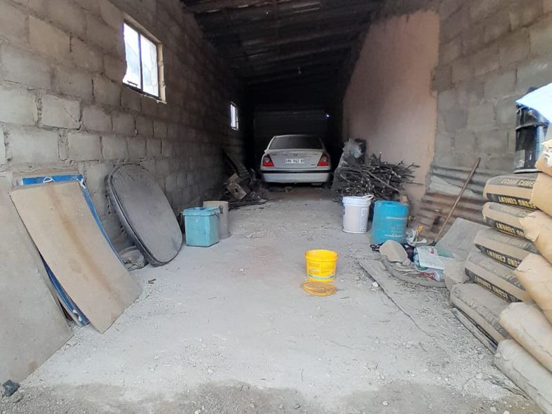 A basic, unfinished garage space featuring exposed timber roof beams, concrete block walls, and a concrete floor, suitable for storage or vehicle parking.