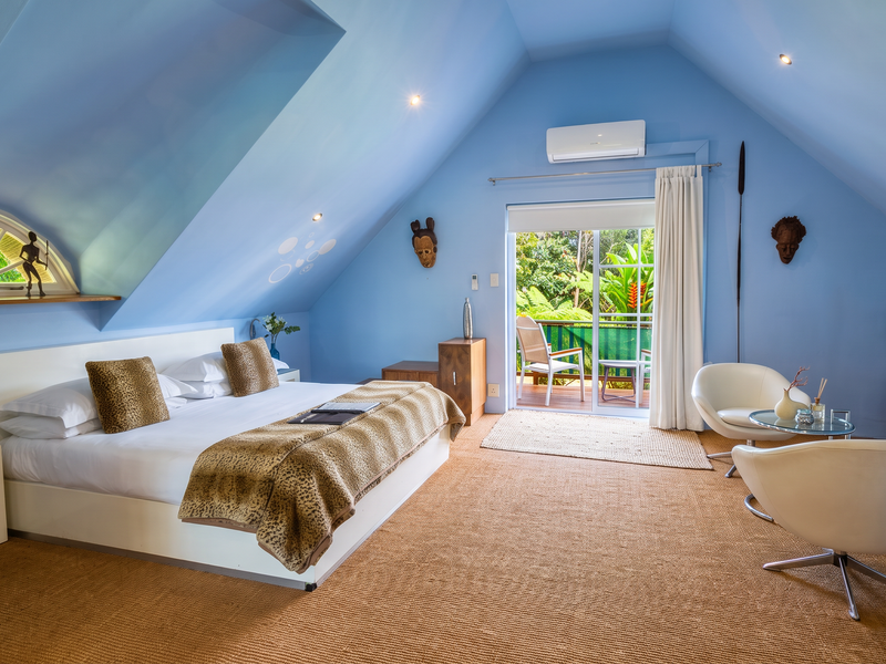 Spacious bedroom featuring a vaulted ceiling, recessed lighting, split-system air conditioning, and a sliding glass door leading to a private balcony.