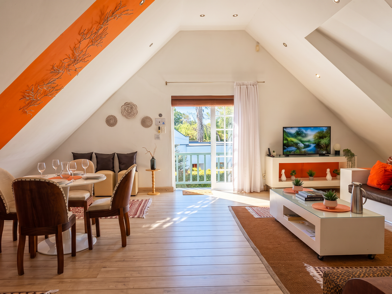 Bright open-plan living and dining area featuring sloped ceilings, laminate flooring, recessed lighting, and direct access to a private balcony.