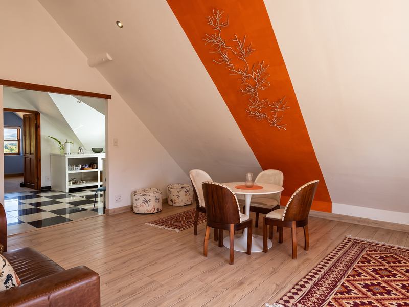 Open-plan living area featuring laminate flooring, a distinctive sloped ceiling with an orange accent stripe, and recessed lighting, leading into an adjacent room.
