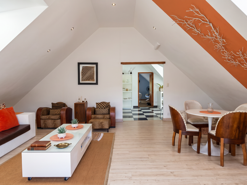 Spacious open-plan attic living and dining area featuring sloped ceilings, skylights, and modern laminate flooring with a bright, airy atmosphere.