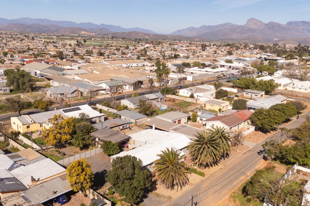 Aerial view of the property and surrounding residential neighbourhood, showcasing the roof structure, solar panels, and street access.