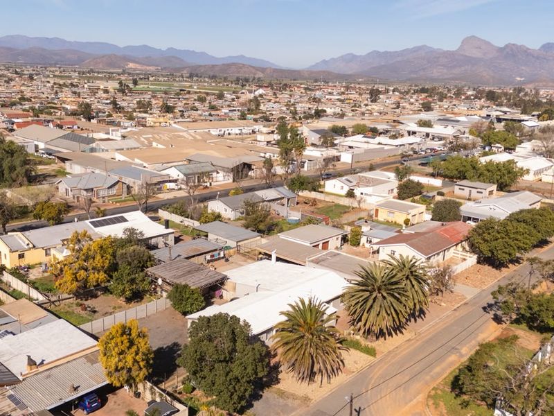Aerial view of the property and surrounding residential neighbourhood, showcasing the roof structure, solar panels, and street access.