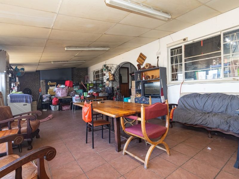 A spacious covered patio area featuring tiled flooring and fluorescent lighting, offering potential for a comfortable outdoor entertainment space.