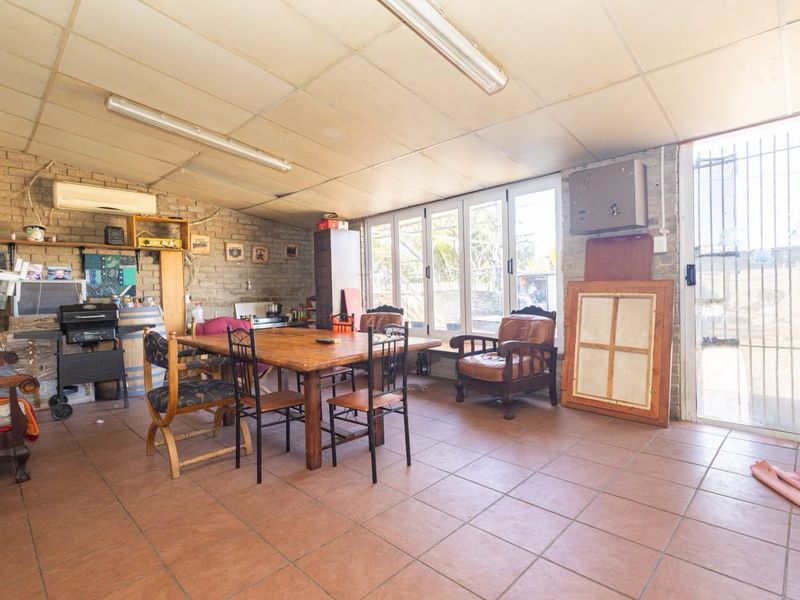 Spacious living area featuring exposed brick walls, tiled flooring, and direct access to the exterior through glass sliding doors with security gates.