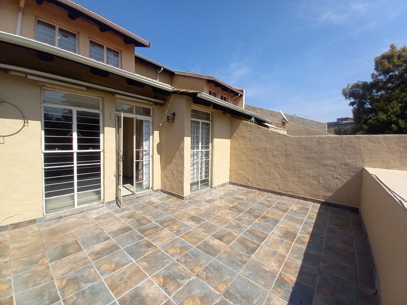A spacious open-air patio featuring tiled flooring, secure access points, and a private boundary wall, ideal for outdoor relaxation and entertaining.
