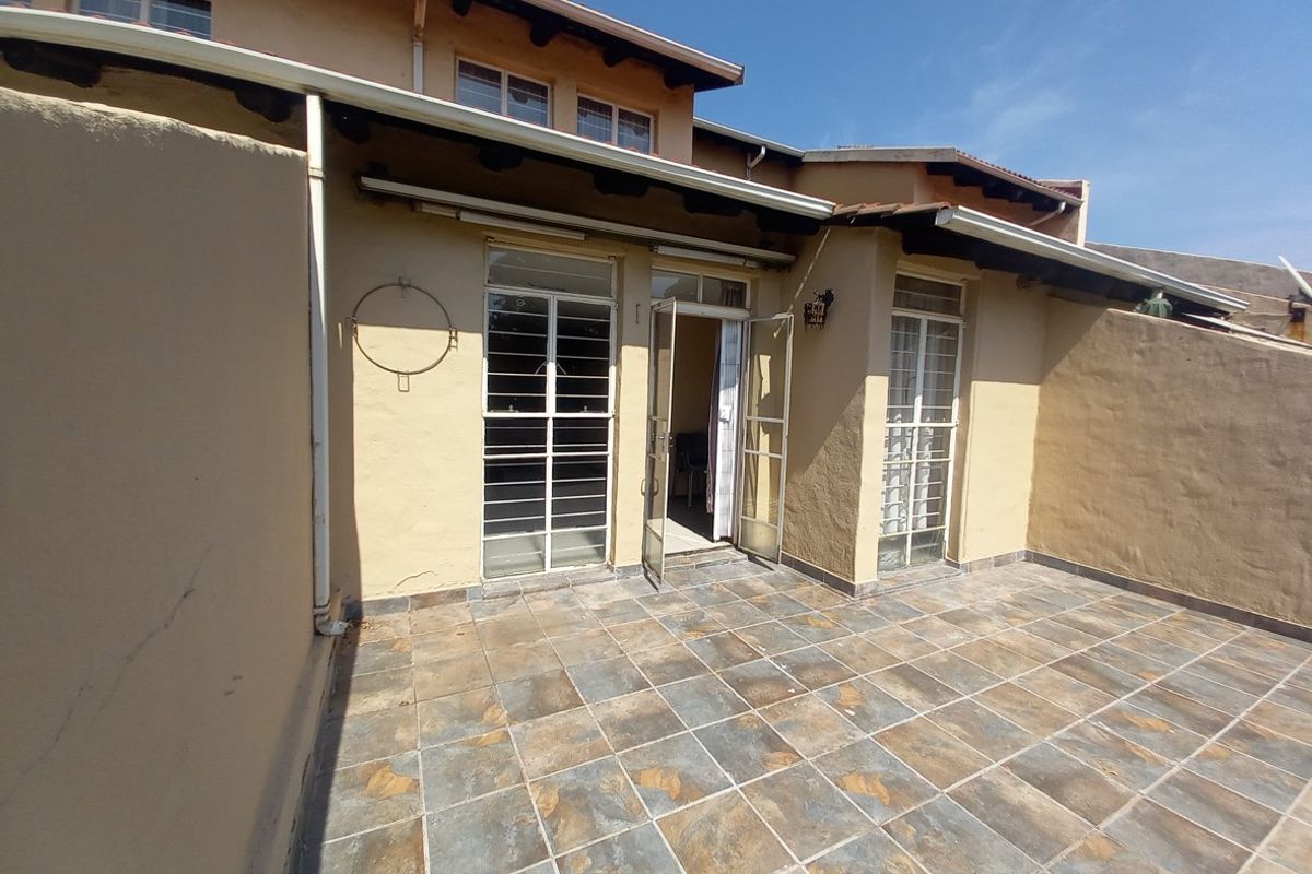 A private rear patio area featuring tiled flooring, security gates, and direct access to the interior living space.