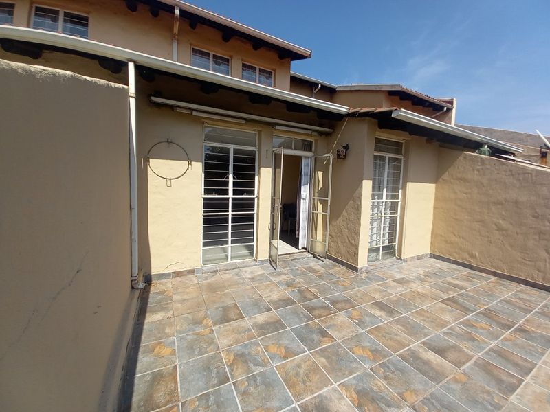 A private rear patio area featuring tiled flooring, security gates, and direct access to the interior living space.