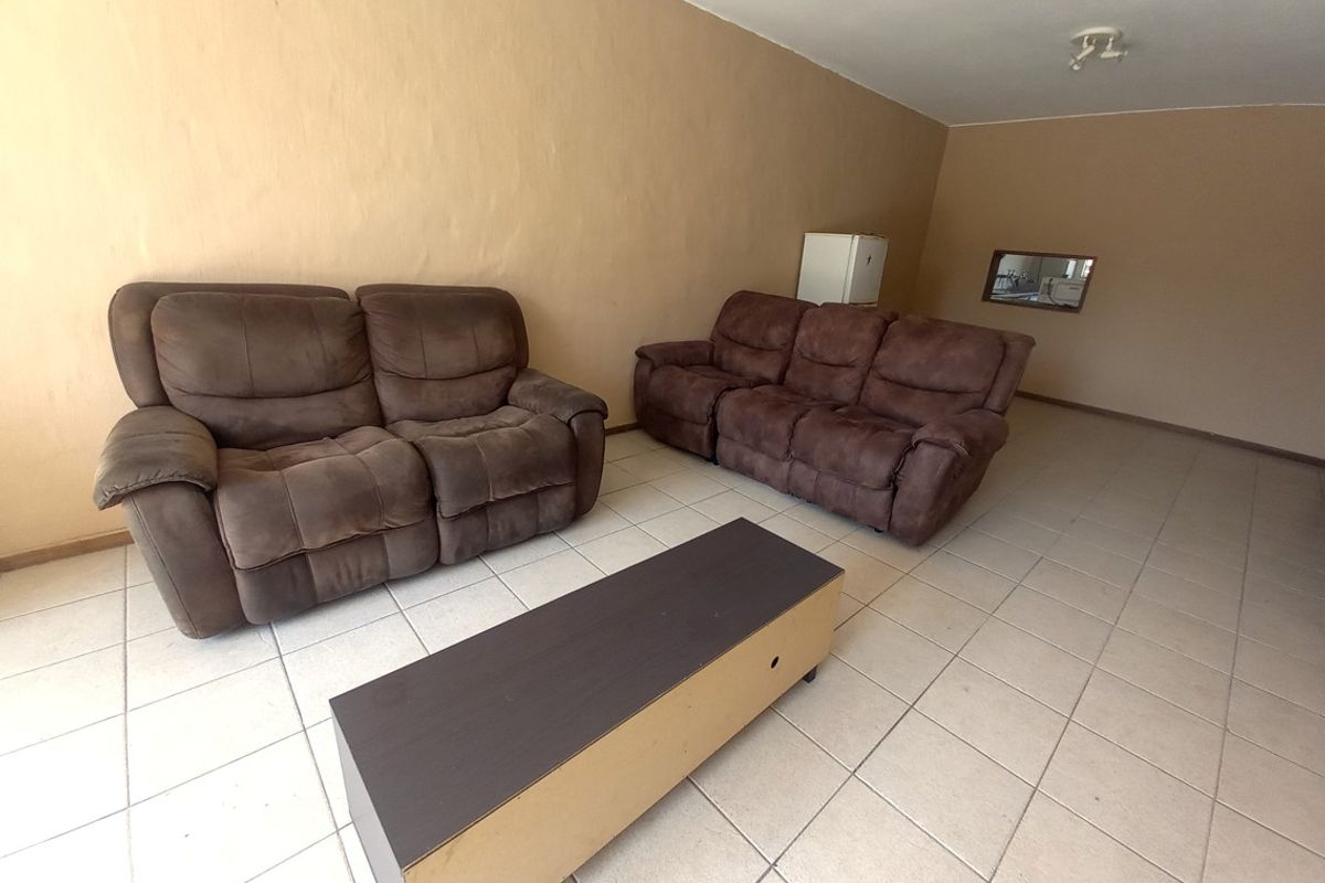A spacious living room featuring neutral wall tones and ceramic floor tiles, offering a blank canvas for potential interior updates and modern styling.