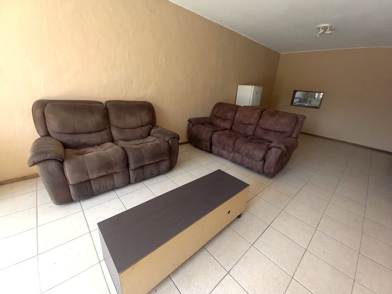 A spacious living room featuring neutral wall tones and ceramic floor tiles, offering a blank canvas for potential interior updates and modern styling.