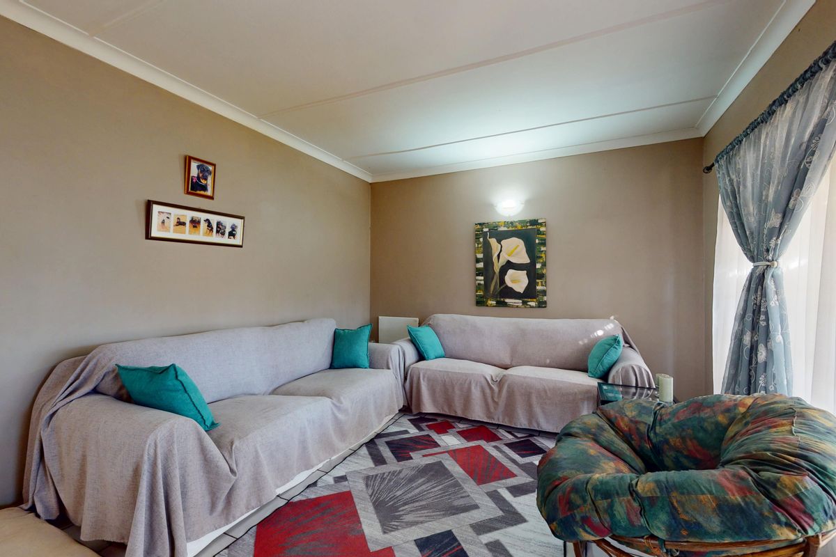 A comfortable living room featuring neutral wall tones, coved ceiling detailing, and a wall-mounted light fixture, providing a functional and inviting space.