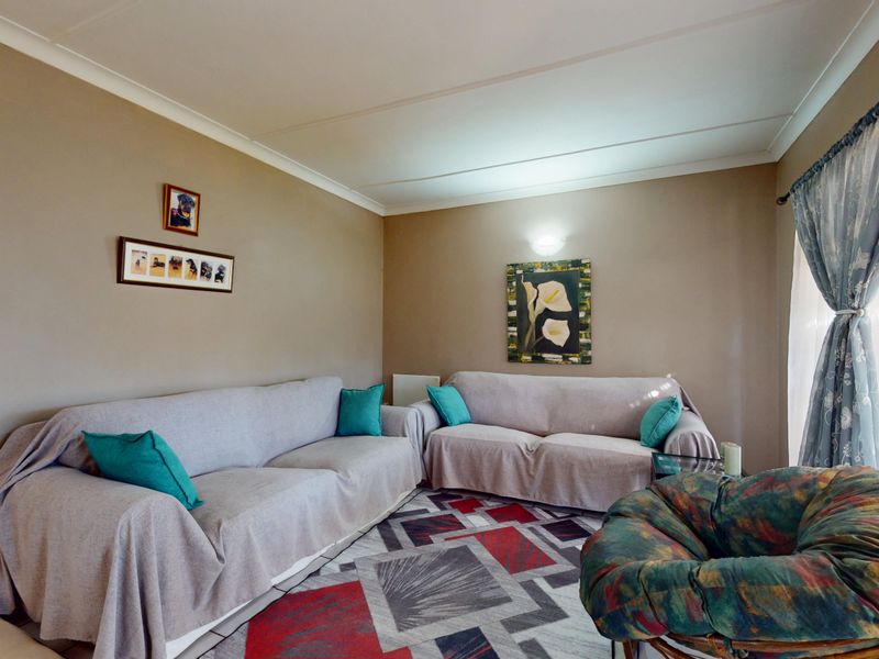 A comfortable living room featuring neutral wall tones, coved ceiling detailing, and a wall-mounted light fixture, providing a functional and inviting space.