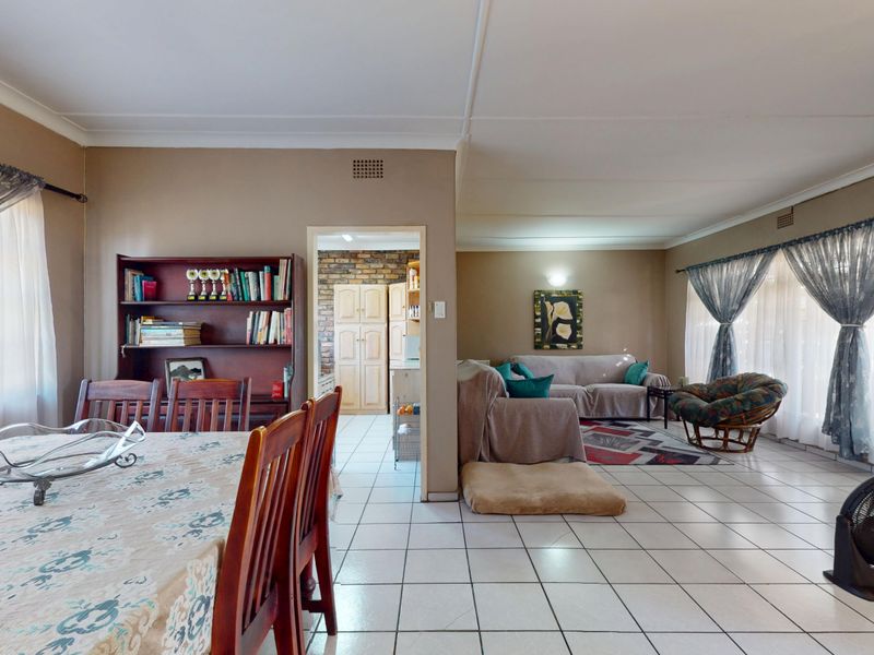 Spacious open-plan living and dining area featuring neutral wall tones, ceramic floor tiling, and a seamless transition to the adjacent kitchen space.