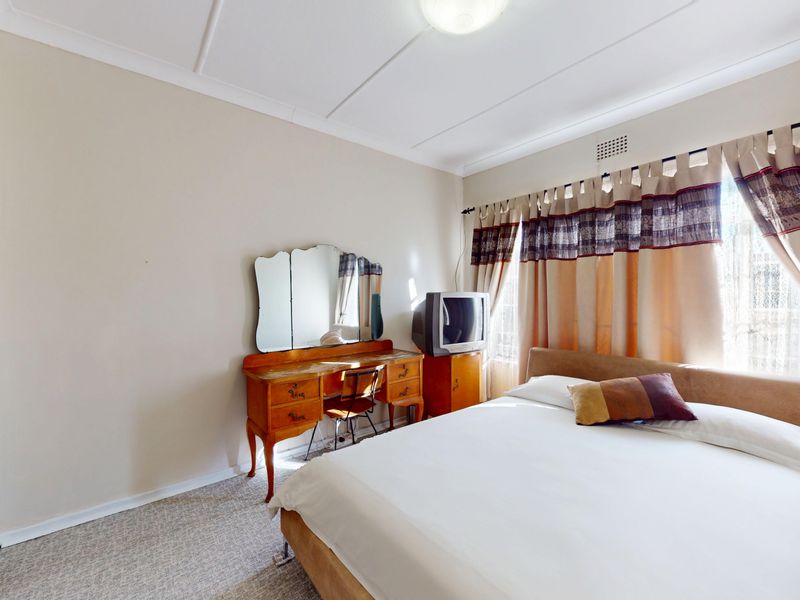 A functional bedroom featuring neutral walls, carpeted flooring, and a built-in wardrobe, offering a comfortable and practical living space.