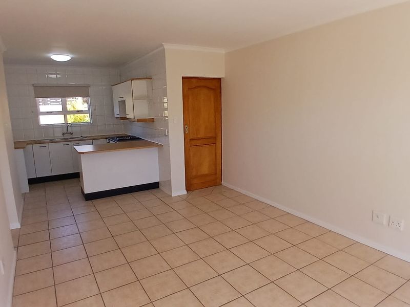 An open-plan living and kitchen area featuring tiled flooring, built-in cabinetry with a laminate countertop, and a gas hob.