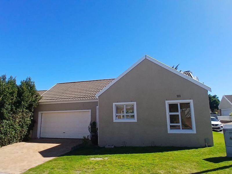 Front elevation of a single-story residential house featuring a tiled roof, attached garage, paved driveway, and well-maintained lawn.