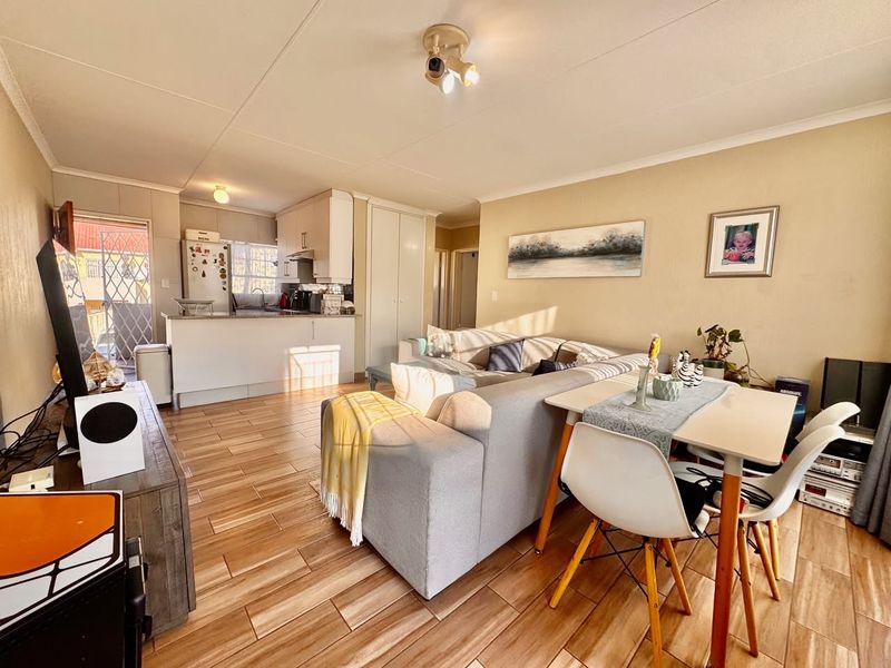 Open-plan living and dining area featuring tiled flooring and an integrated kitchen with built-in cabinetry and counter space.