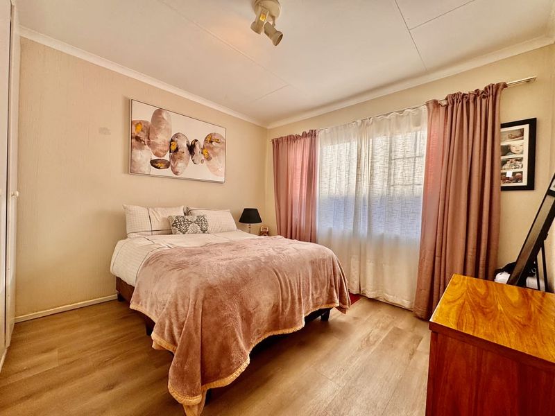 A well-maintained bedroom featuring laminate flooring, a built-in wardrobe, and natural light through the window.