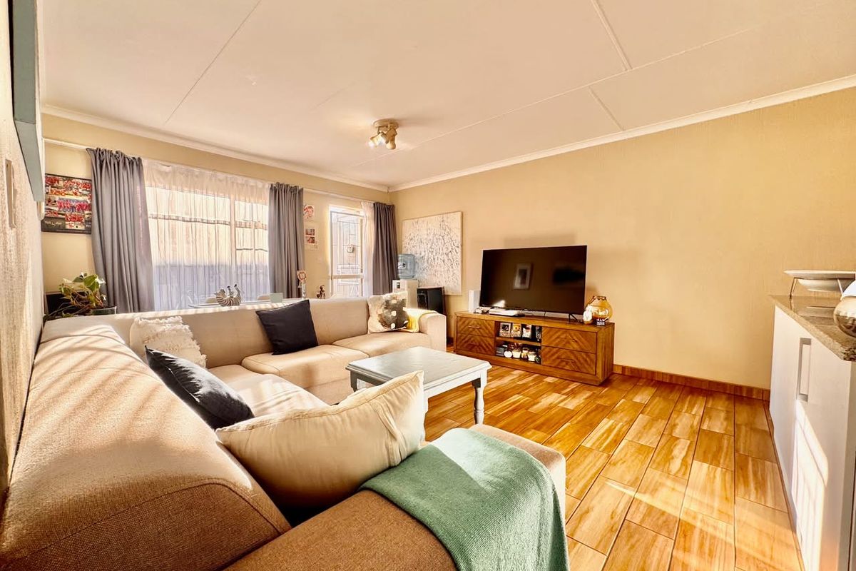 A bright living room featuring tiled flooring and a sliding glass door providing natural light.