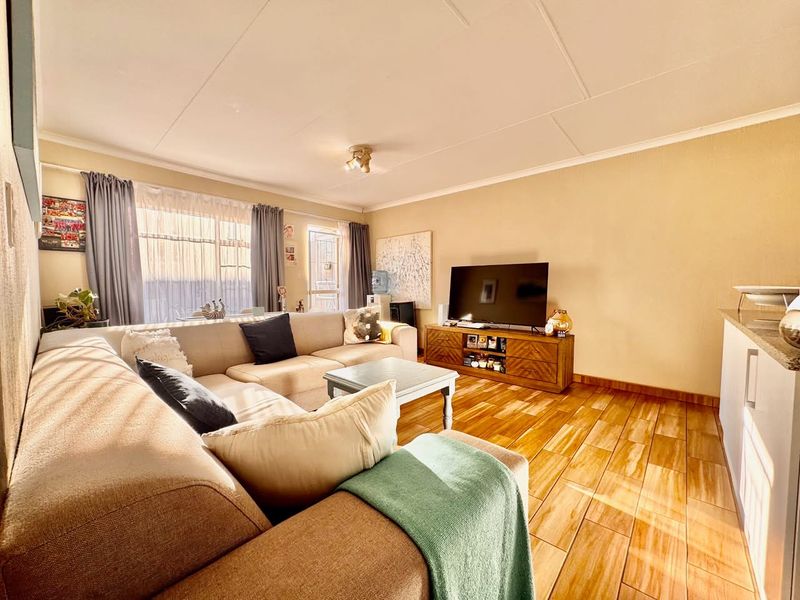 A bright living room featuring tiled flooring and a sliding glass door providing natural light.
