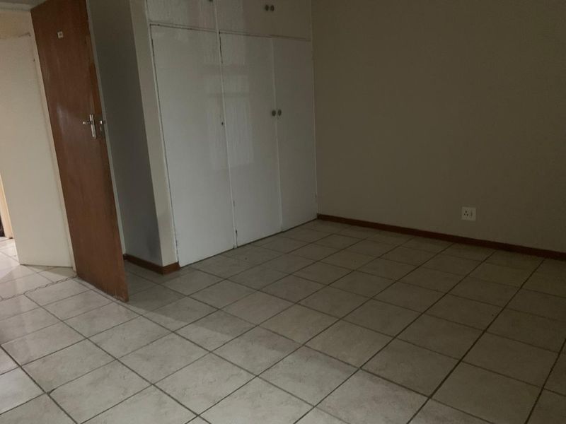 An empty bedroom featuring tiled flooring and built-in cupboards, offering a blank canvas for personalization.