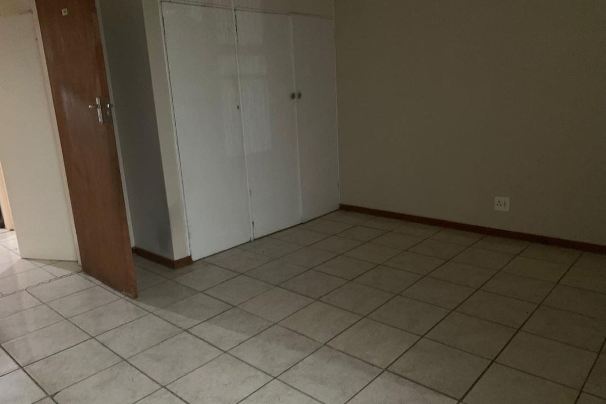 An empty bedroom featuring tiled flooring and built-in cupboards, offering a blank canvas for personalization.