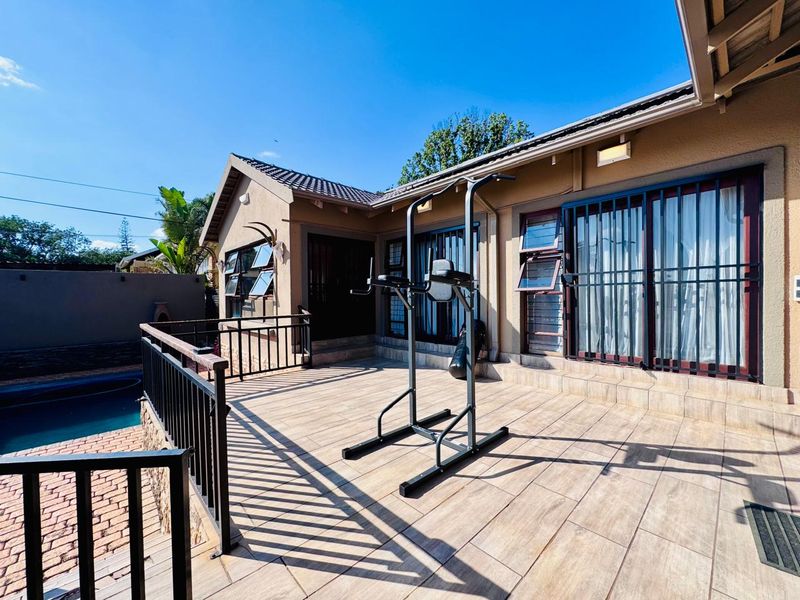 Spacious outdoor patio area featuring tiled flooring, metal safety railings, and direct access to the swimming pool area.