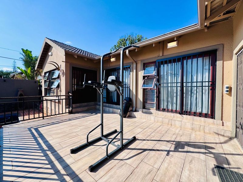 A spacious tiled patio area featuring security bars on windows and doors, providing a functional outdoor living space.