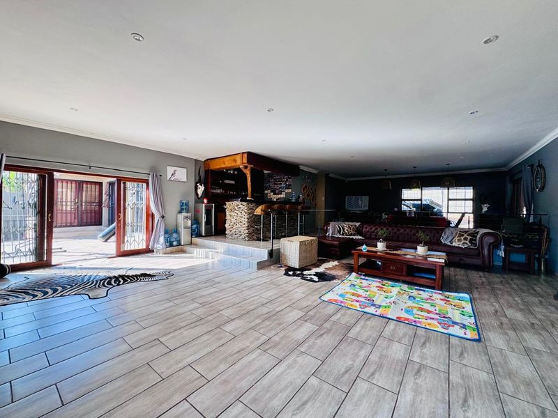 Spacious open-plan living area featuring a built-in stone-clad bar, tiled flooring, and large sliding doors providing seamless access to the outdoor patio.