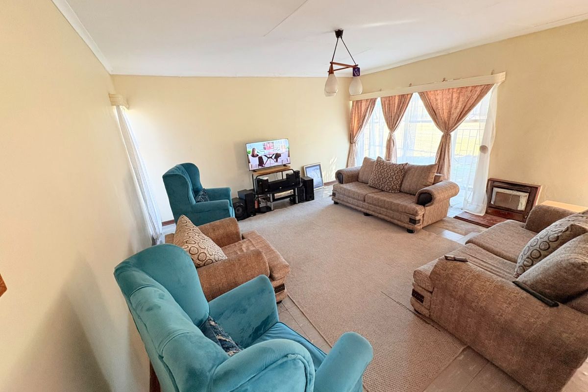 A spacious living room featuring tiled flooring, large windows with natural light, and classic cove cornicing, offering a comfortable area for relaxation.
