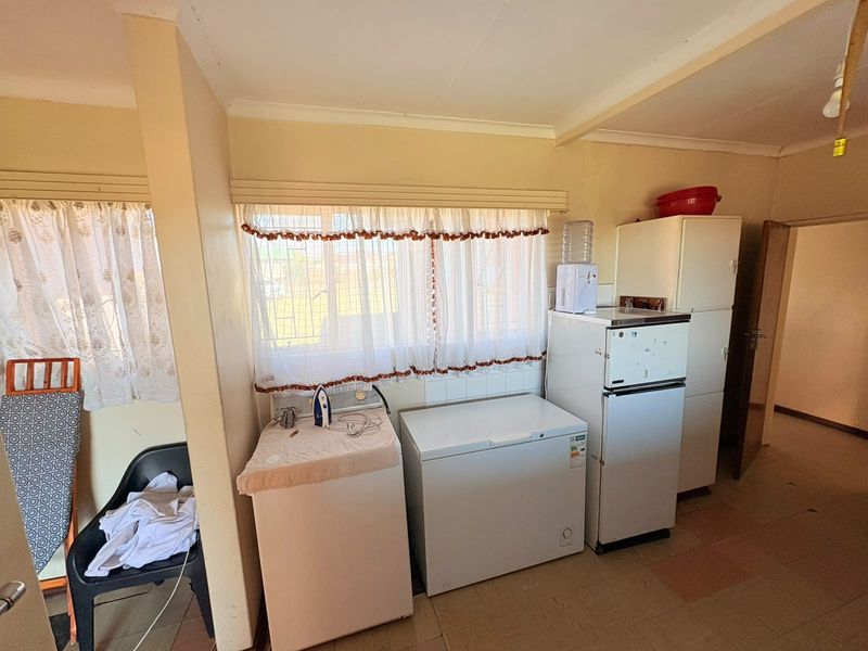 A functional laundry area featuring tiled flooring and a window with security bars, providing a practical space for utility and household tasks.