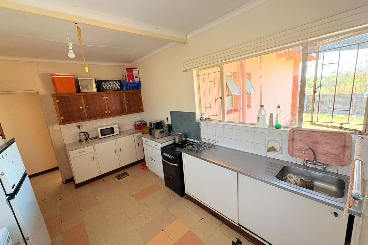 A functional kitchen featuring built-in cabinetry, a stainless steel sink, and a freestanding stove, with large windows providing natural light.