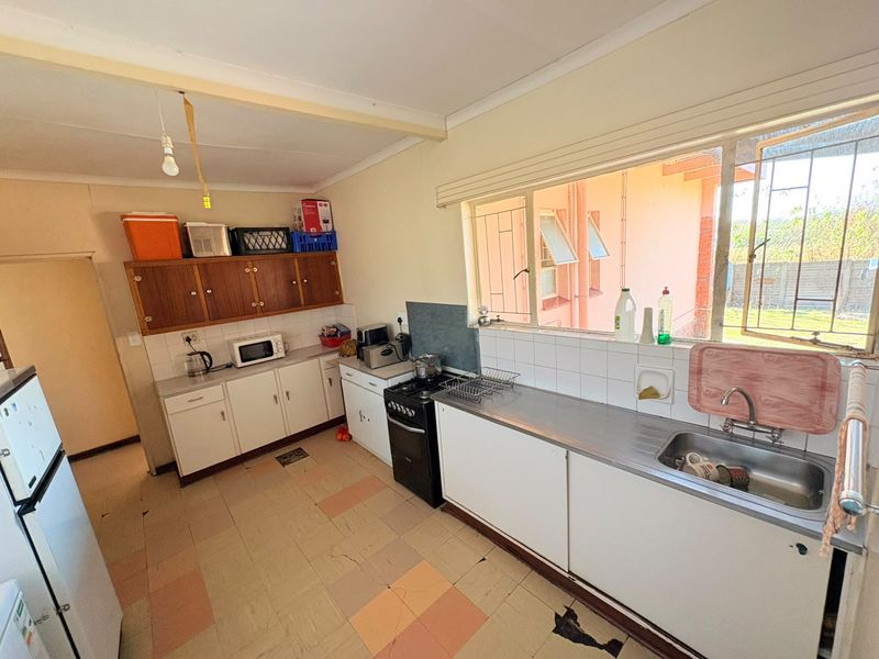 A functional kitchen featuring built-in cabinetry, a stainless steel sink, and a freestanding stove, with large windows providing natural light.