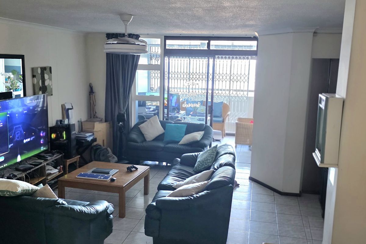 Spacious living room featuring tiled flooring, a ceiling fan, and large sliding glass doors that provide access to an attached balcony.
