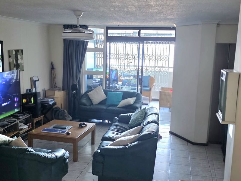 Spacious living room featuring tiled flooring, a ceiling fan, and large sliding glass doors that provide access to an attached balcony.