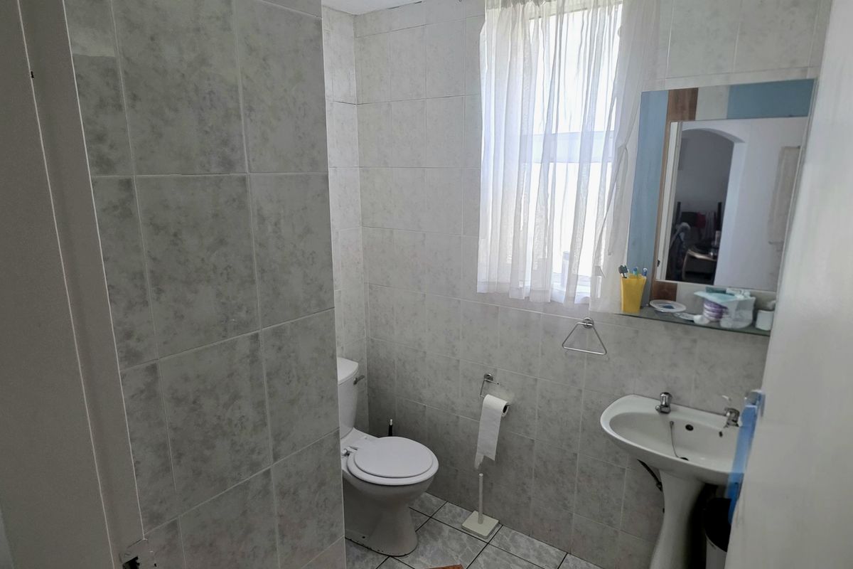A functional bathroom featuring tiled walls and flooring, a pedestal sink, and a standard toilet, providing a clean and practical space.