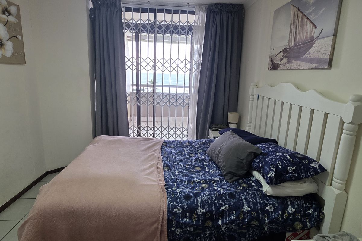 A bedroom featuring tiled flooring and a sliding glass door with a security gate, providing access to an outdoor balcony area.