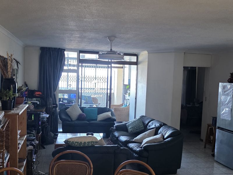 Open plan living area featuring tiled flooring, a ceiling fan, and sliding glass doors leading to an outdoor balcony space.