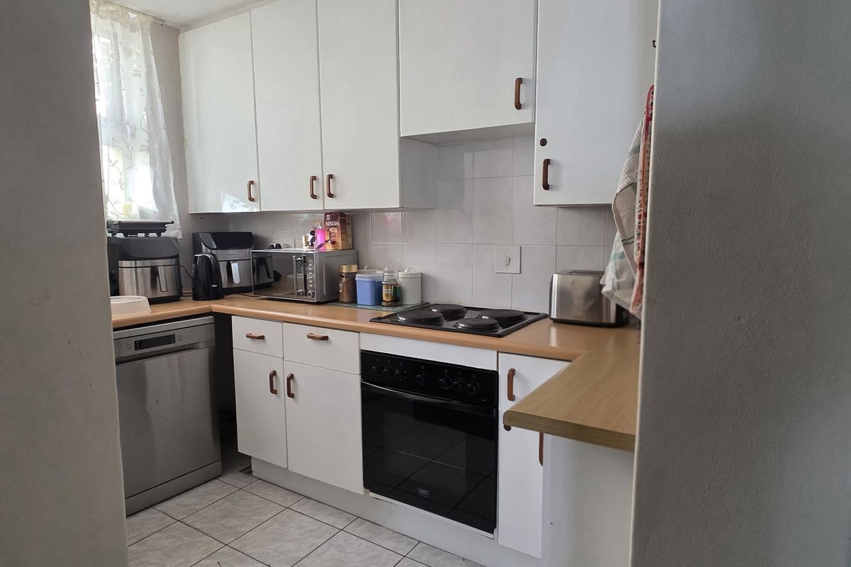 A functional kitchen featuring white cabinetry, laminate countertops, a built-in oven with electric hob, and tiled flooring.