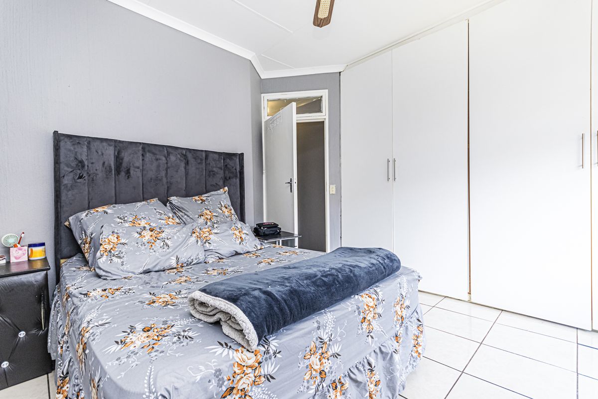 A bedroom featuring tiled flooring, a ceiling fan, and ample built-in cupboard storage space.